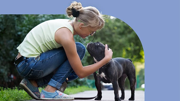 Woman crouching down to pat her dog while out walking